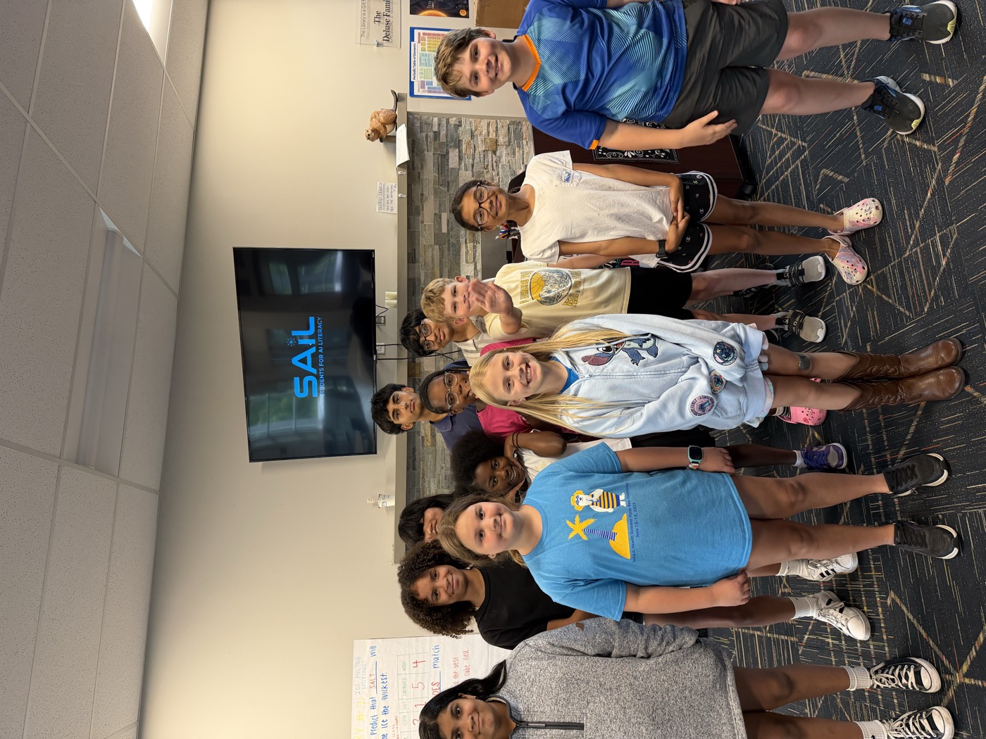 Students gathered in front of a screen displaying the SAIL logo at the Boys & Girls Club